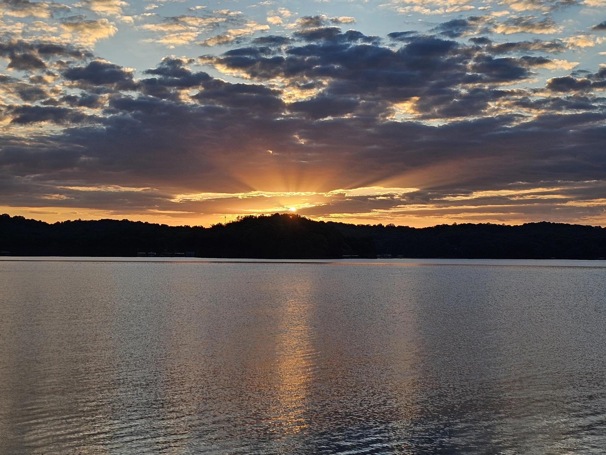 The sun crowning the hills — even hidden behind clouds, the light finds a way through.